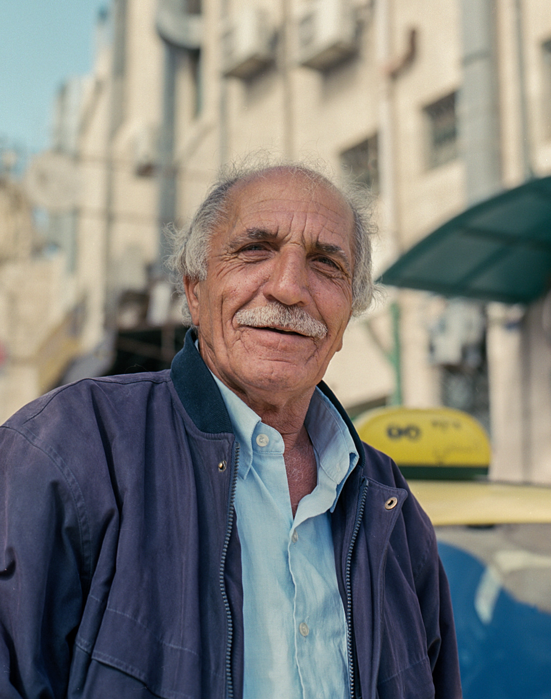 A taxi driver standing in the street.