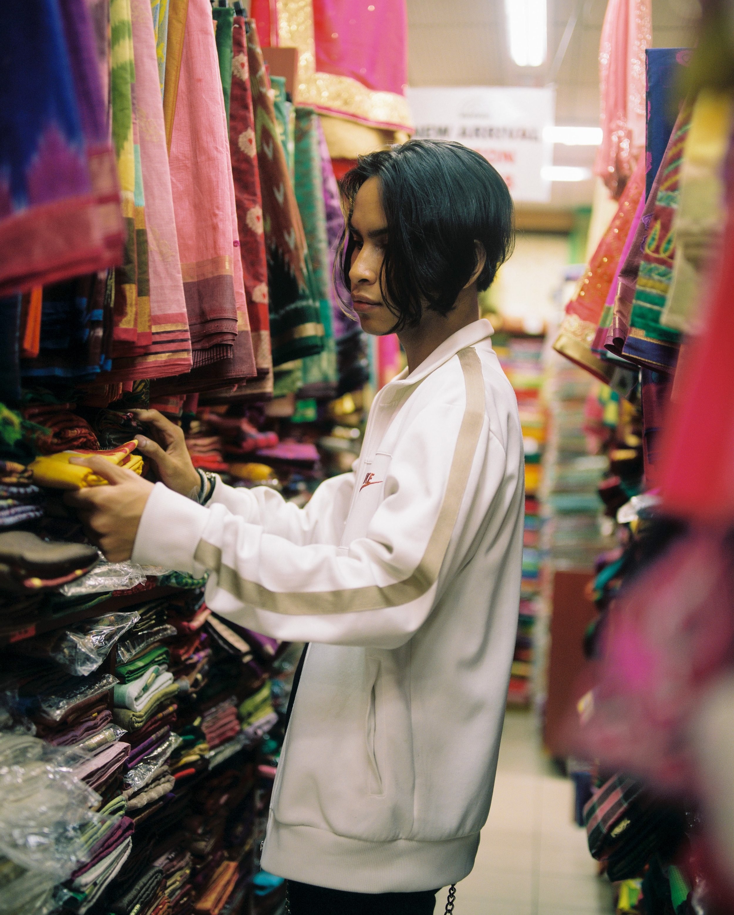 Kash searching through fabric in a shop.