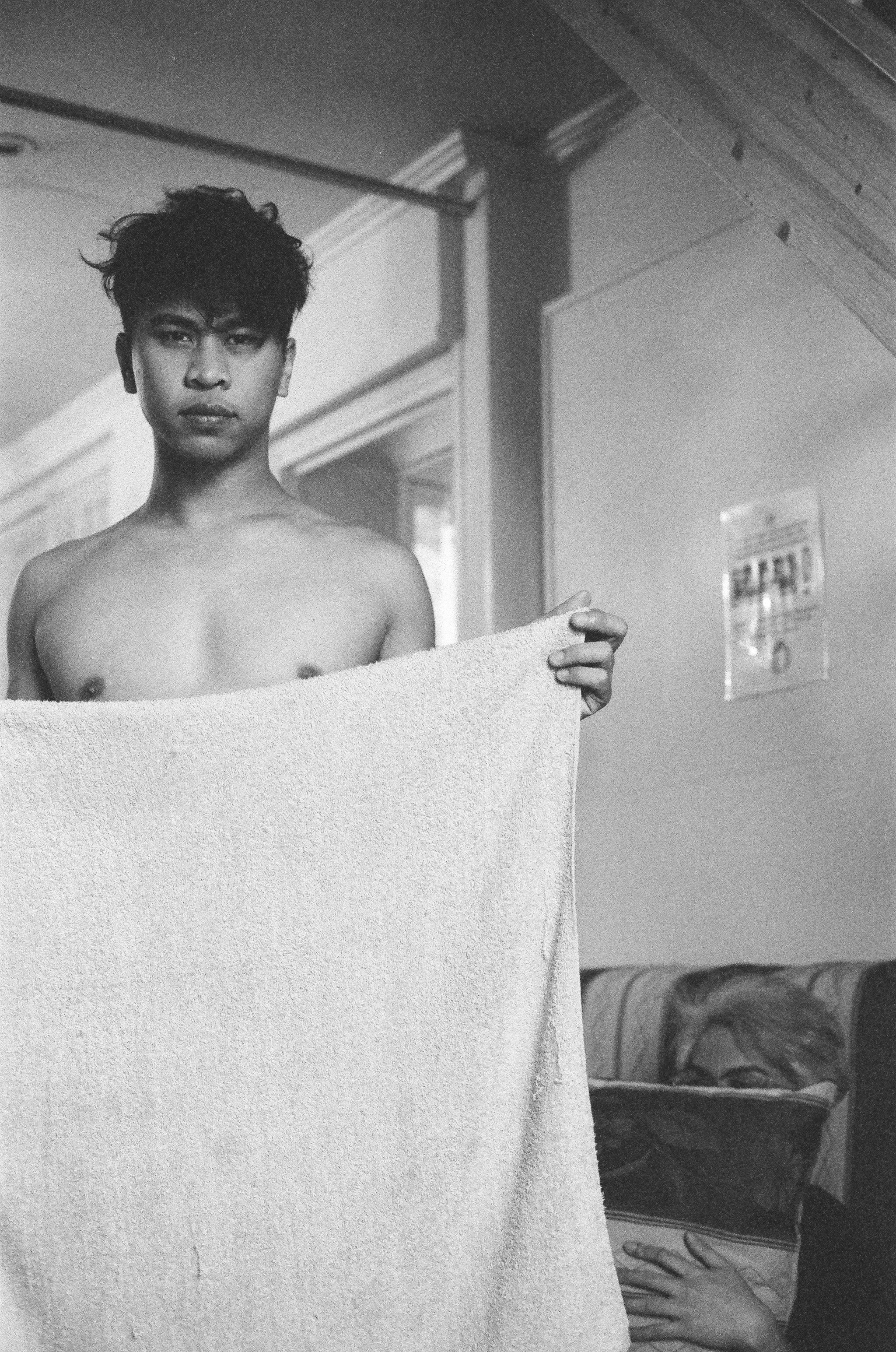 Black-and-white portrait of a person holding a towel.