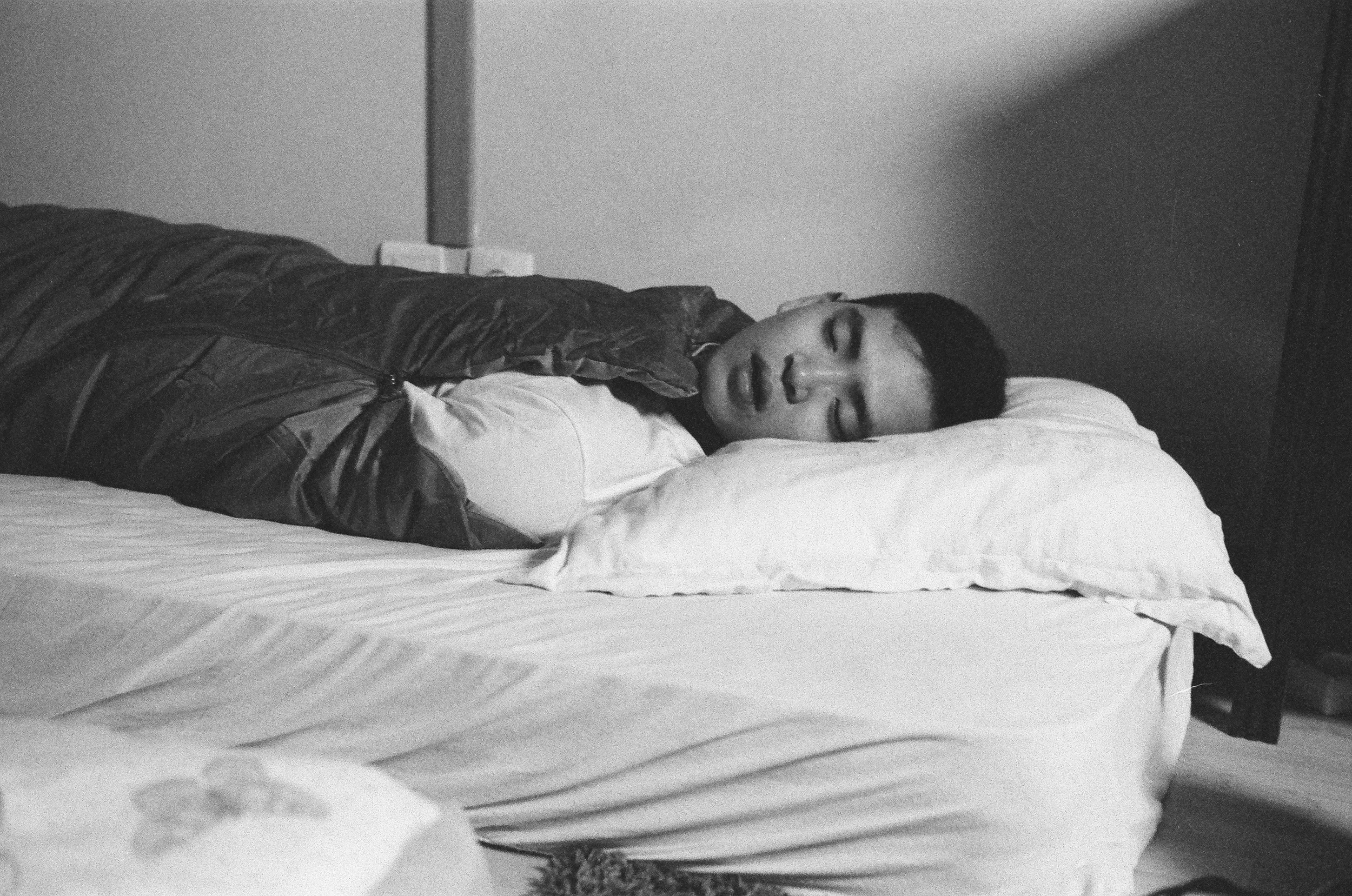 Black-and-white image of a person resting on a bed.