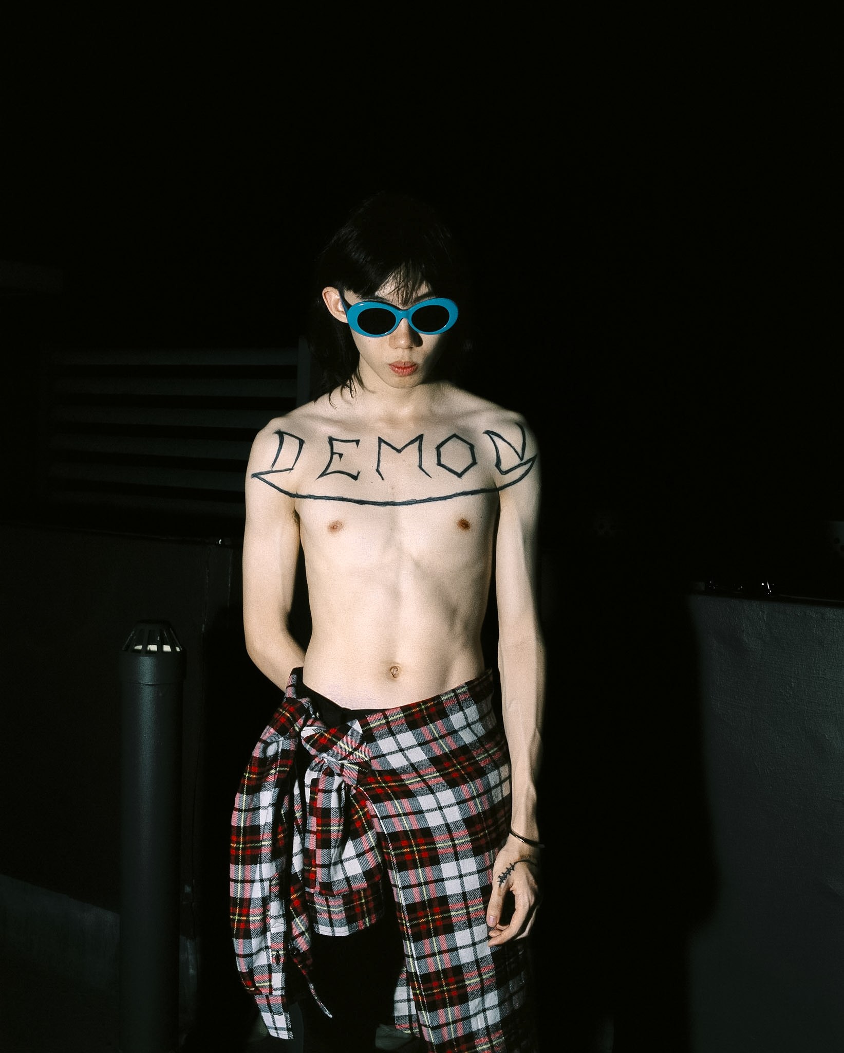 Kai in blue glasses with DEMON written across their chest.