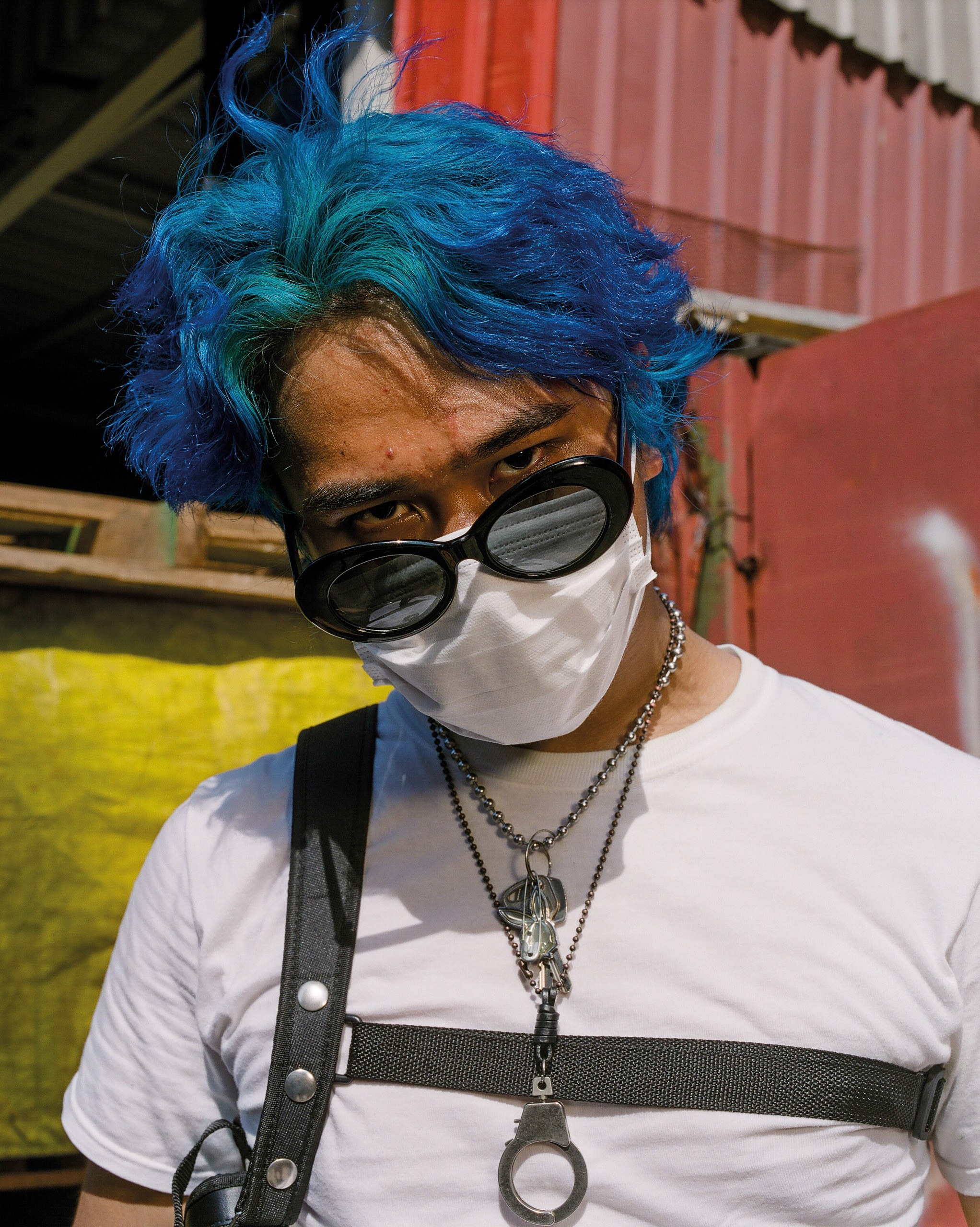 Taufiq with blue hair, sunglasses and a face mask.