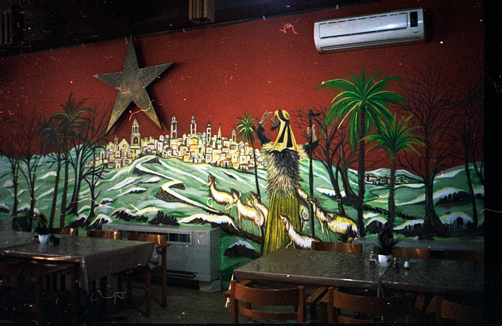 Tables and chairs beneath a brightly painted mural.