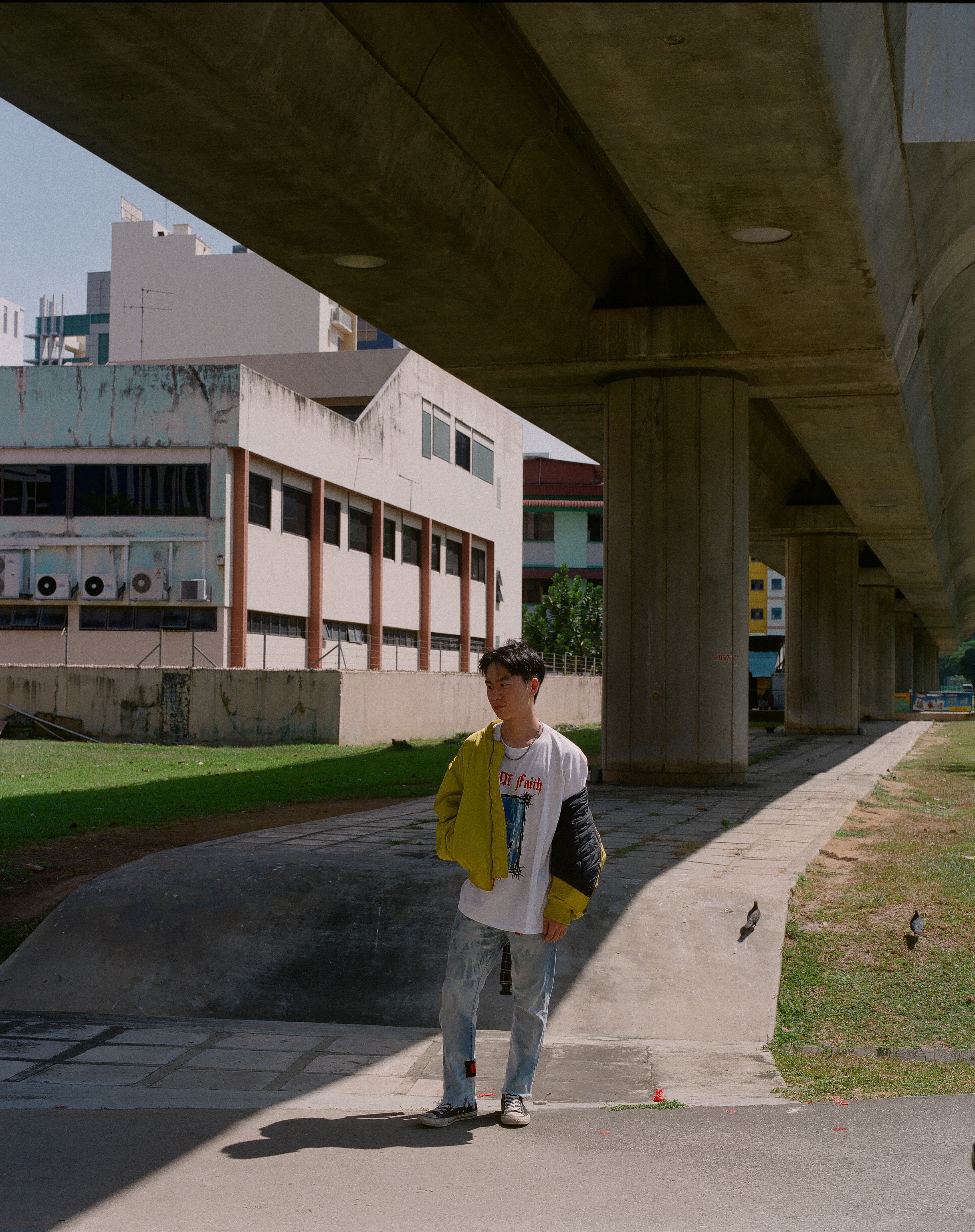 A person in a yellow jacket beneath an elevated concrete railway.