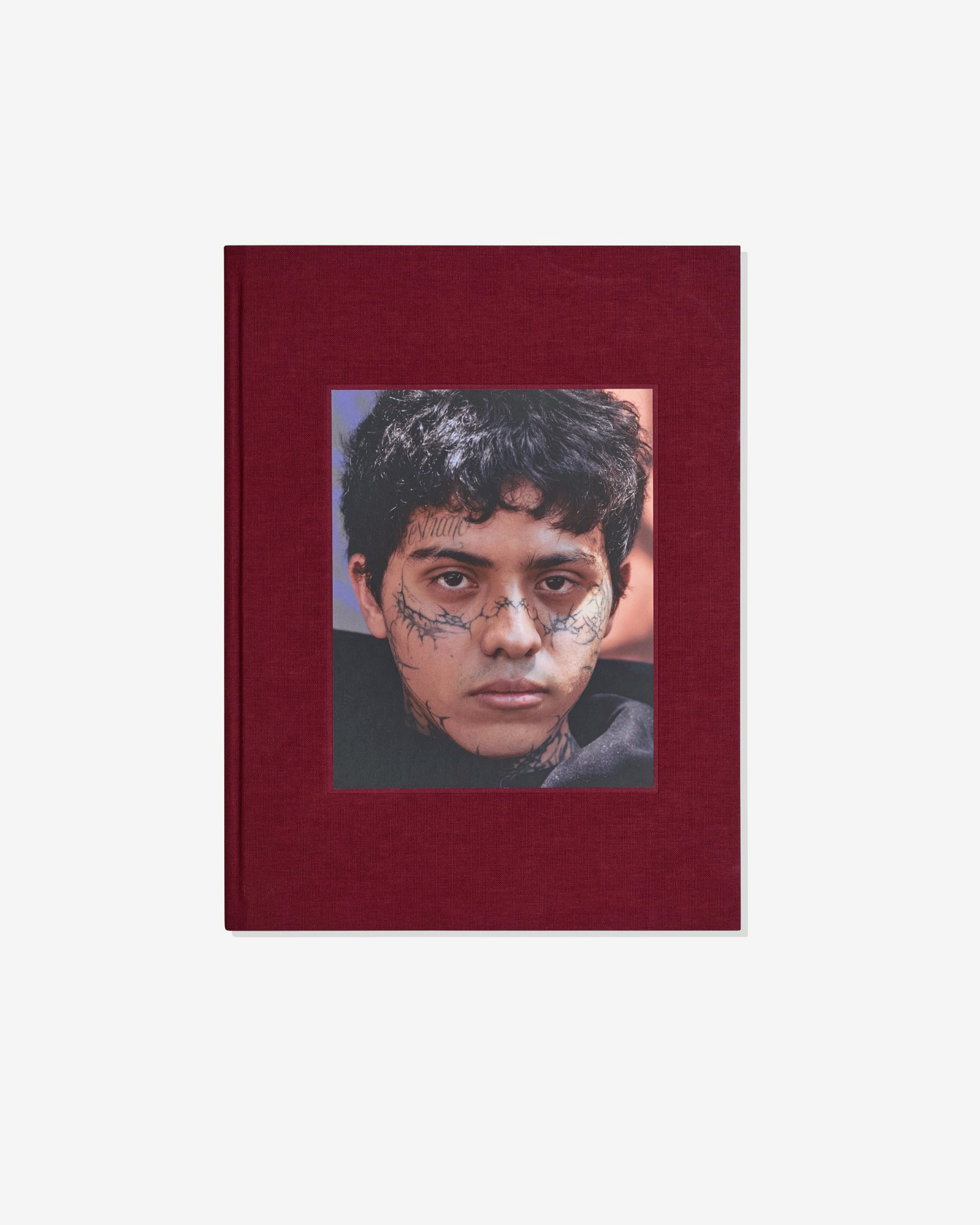 Front of the burgundy clothbound book A Caged Dog Barks the Fiercest with a tipped-in portrait.