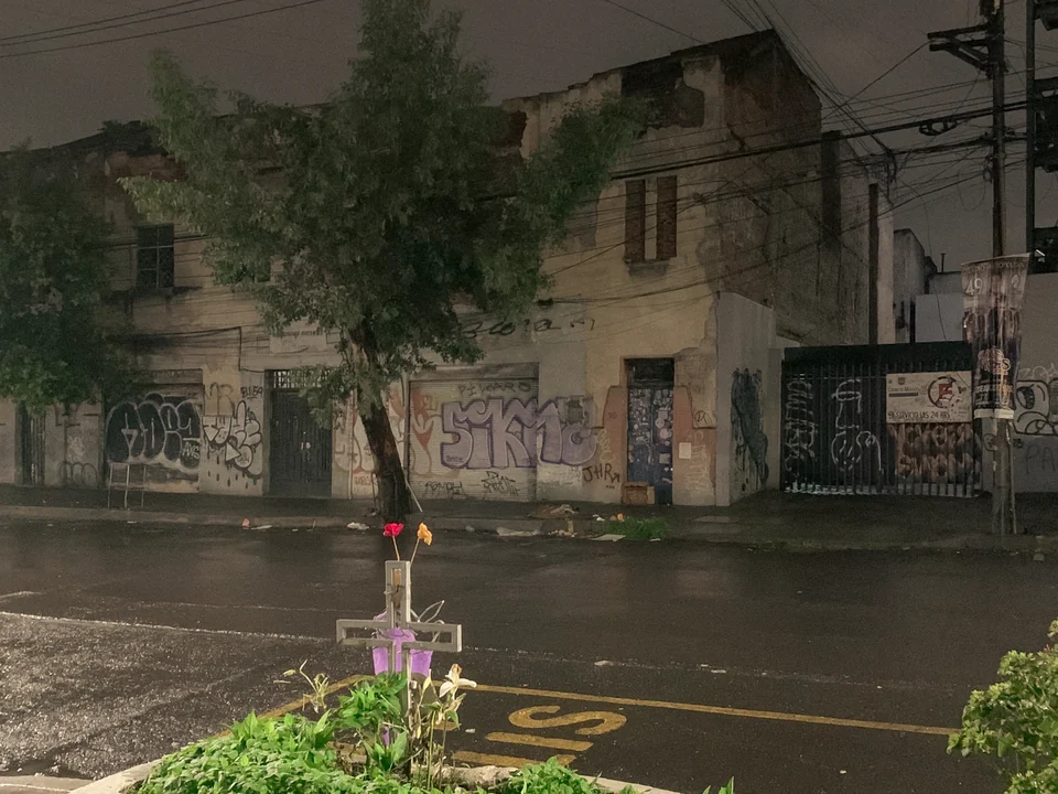 A wet street and worn buildings at night, Mexico City, 2024.
