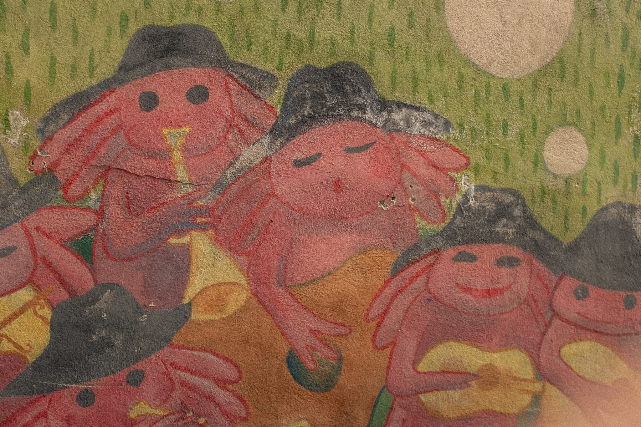 Painted image of three red-faced figures in a green landscape, Mexico City, 2024.