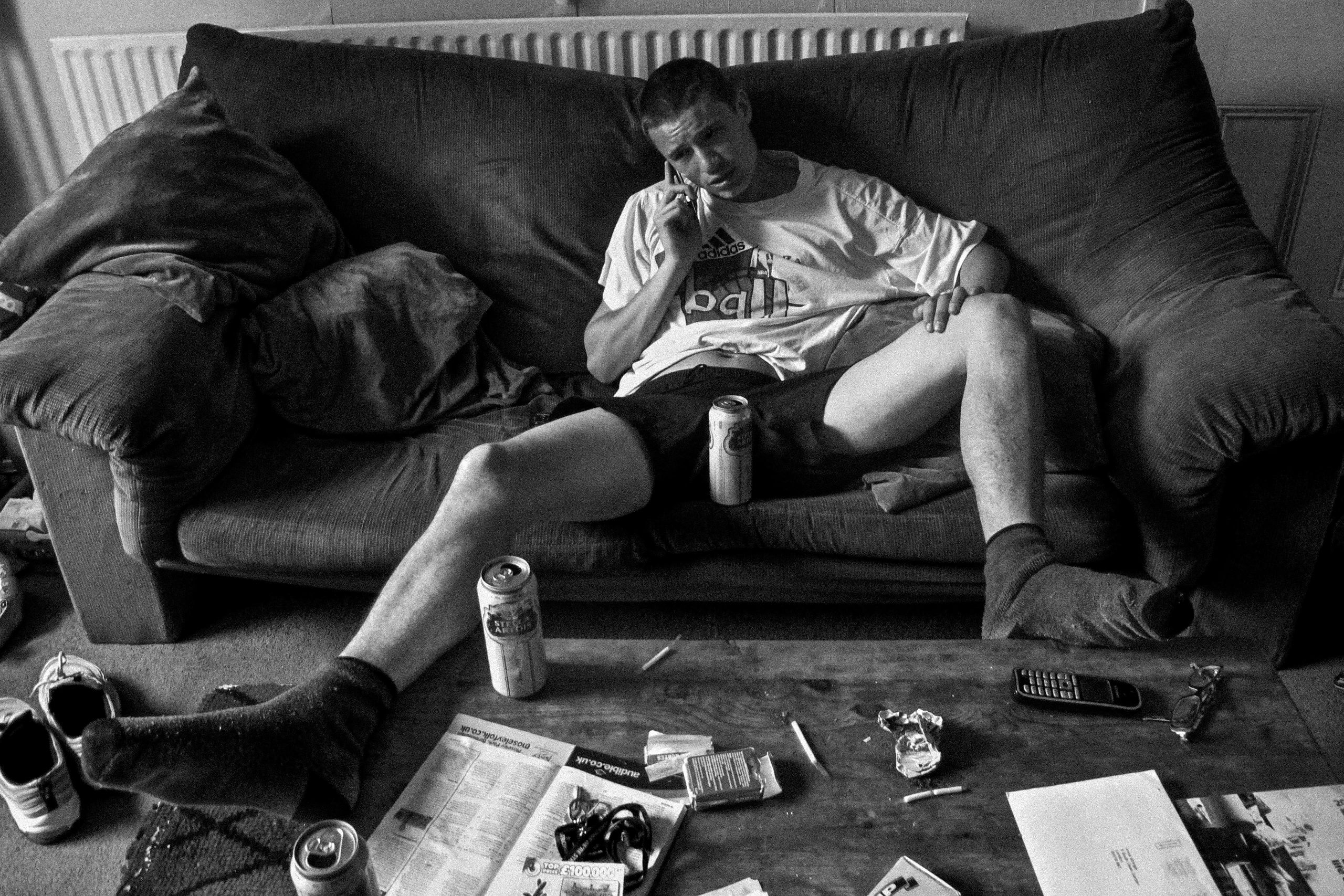 Black-and-white photograph: a person sitting on a sofa in a living room.