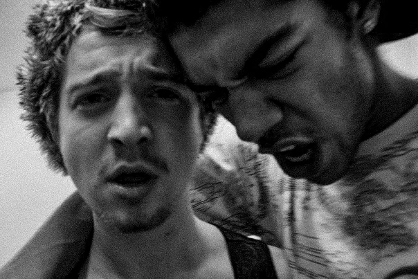 Black-and-white photograph: two friends leaning close to the camera.
