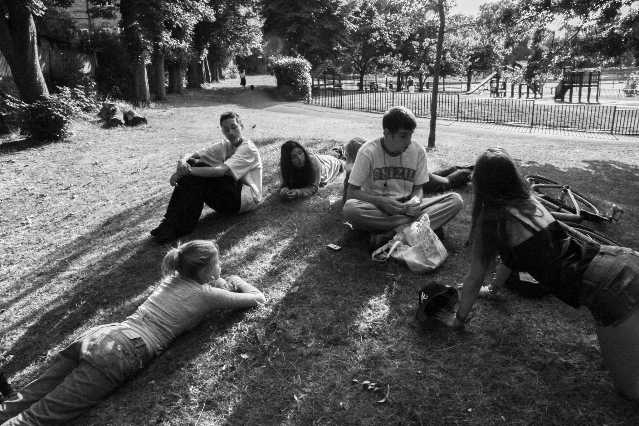 Black-and-white photograph: friends sitting and lying on the grass.