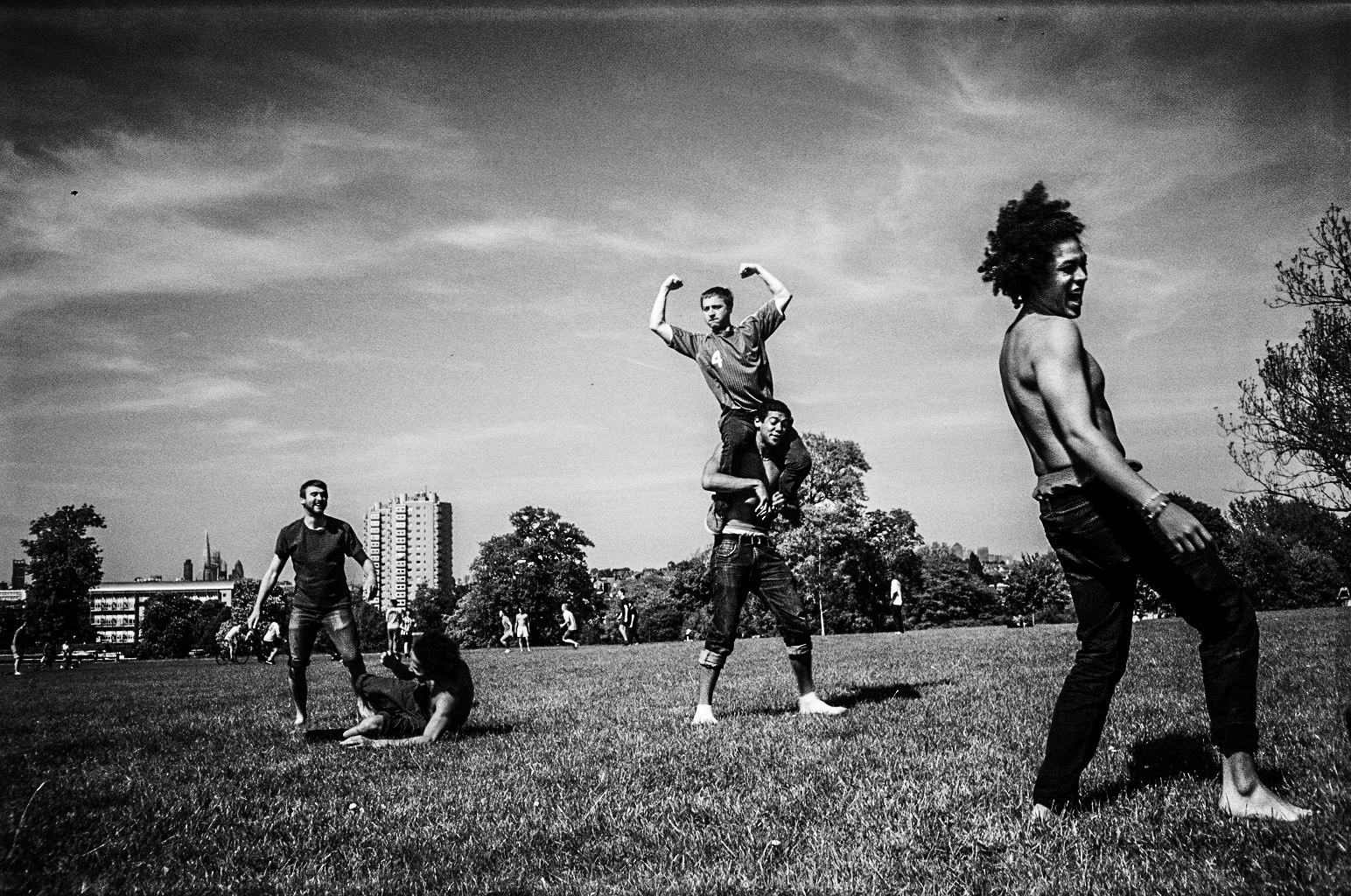 Black-and-white photograph: people moving across an open grassy space.
