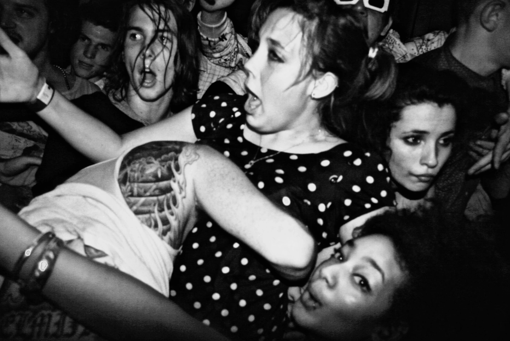 Black-and-white photograph: people dancing closely in a crowded room.