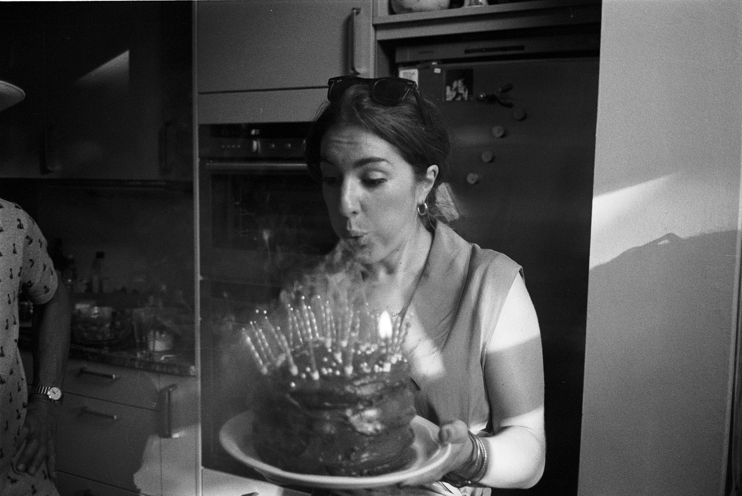 Black-and-white photograph: a person blowing out candles on a birthday cake.