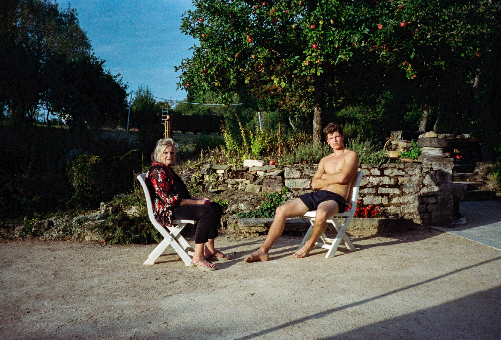 Two people seated in sunny yard.