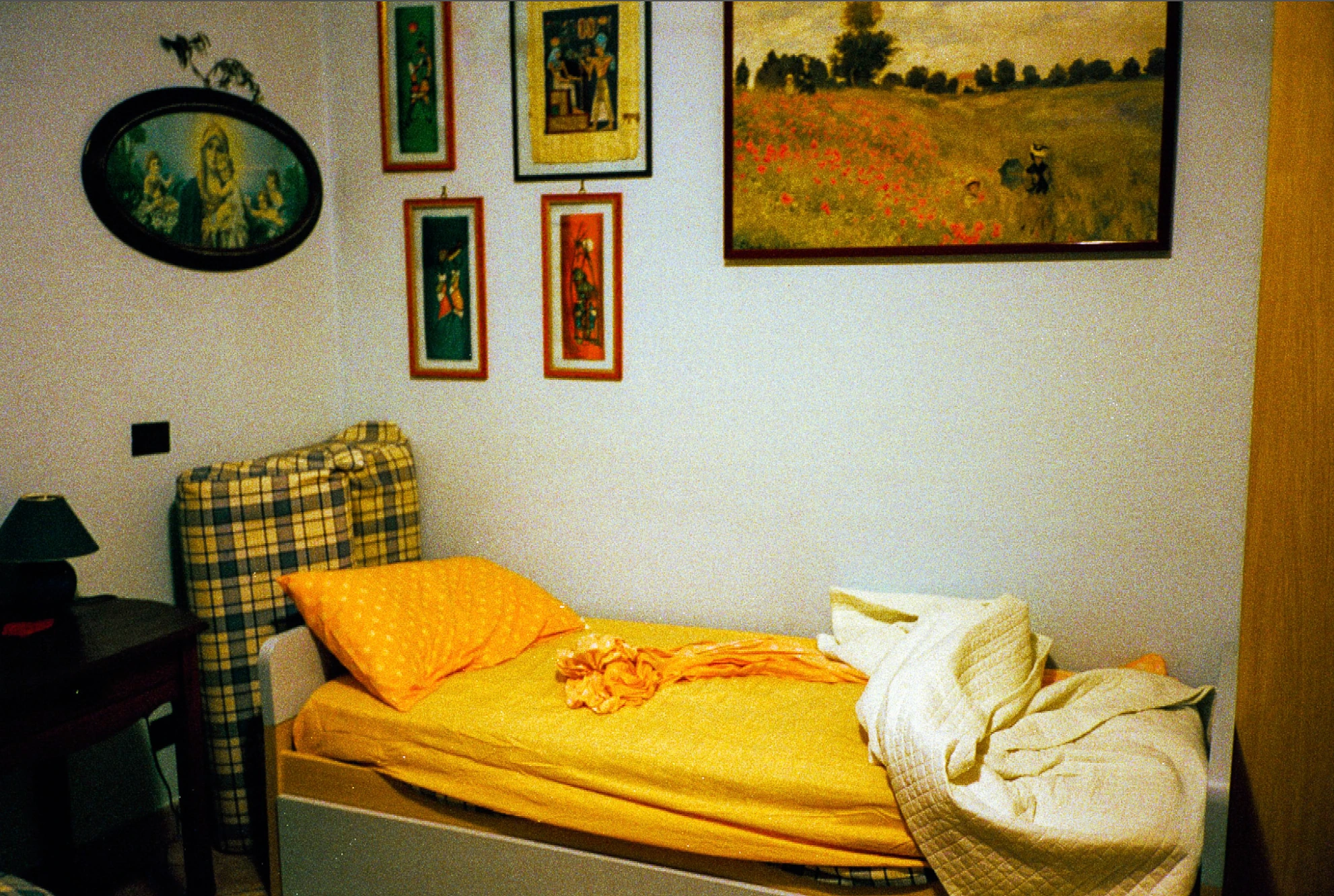 Yellow bed beneath framed pictures.