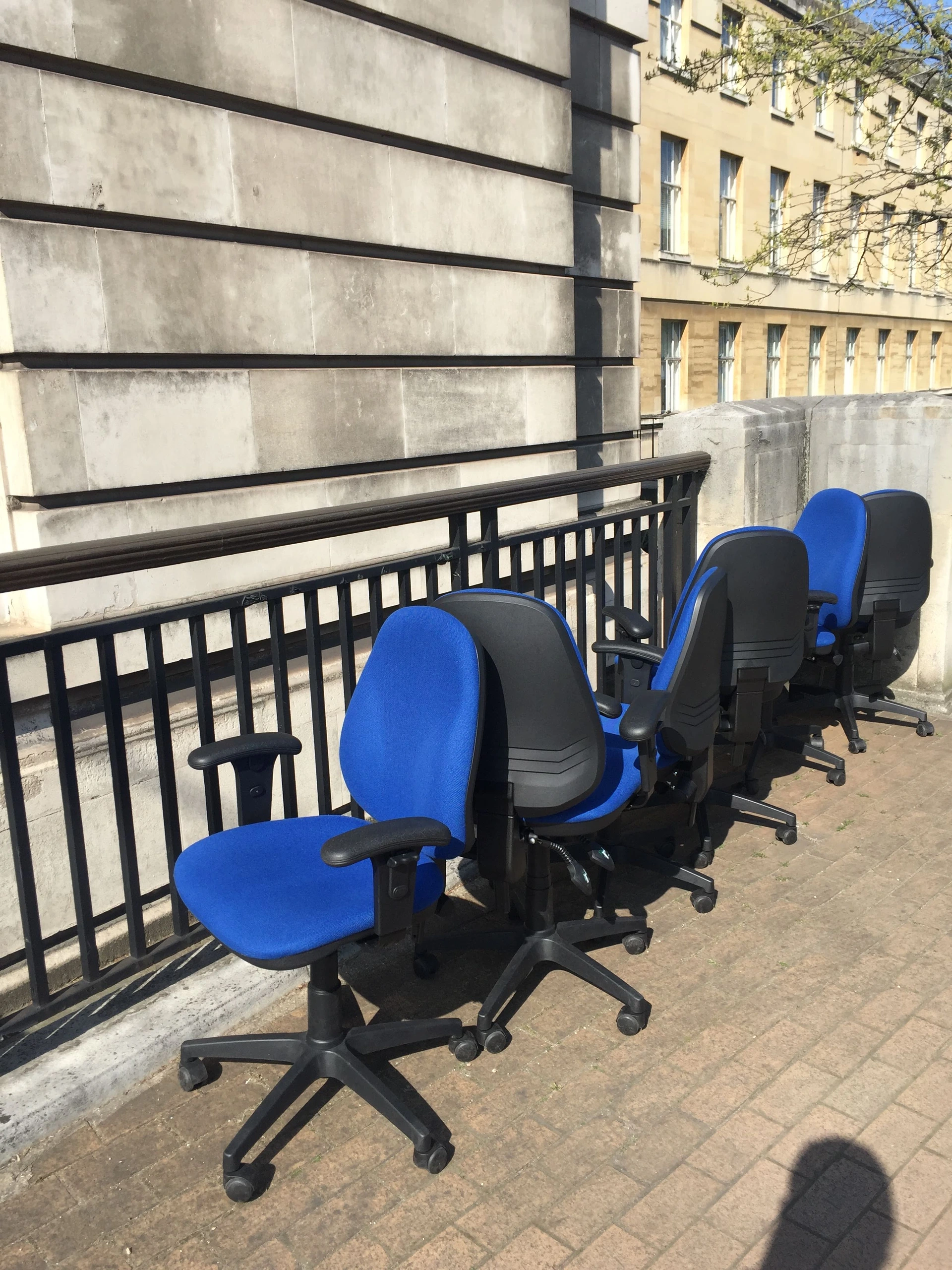 Blue office chairs on pavement.