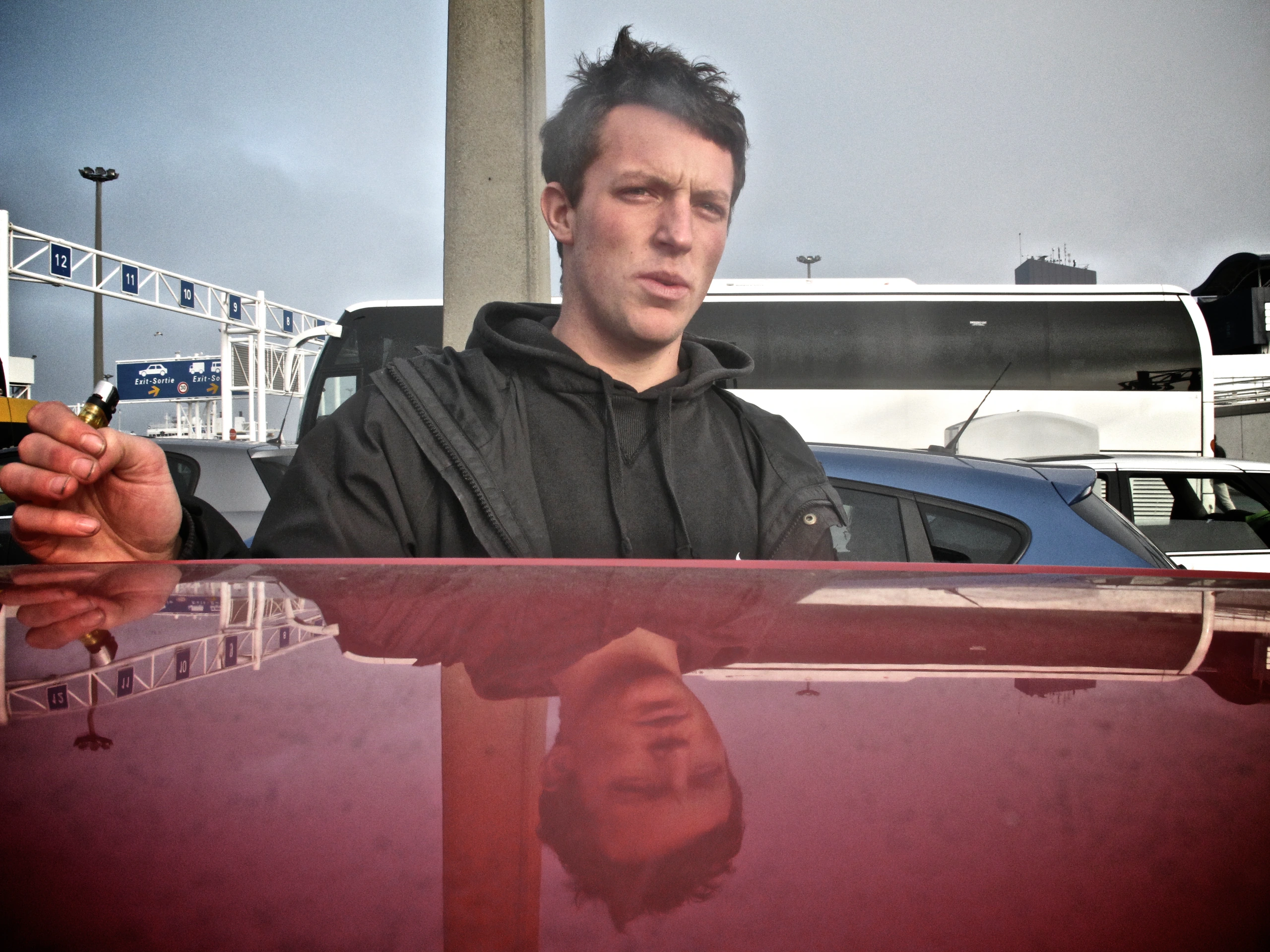 Man reflected on red car roof.
