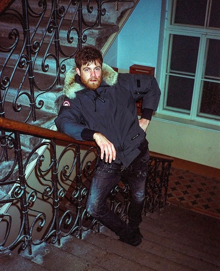 Seated man beside ornate railing.