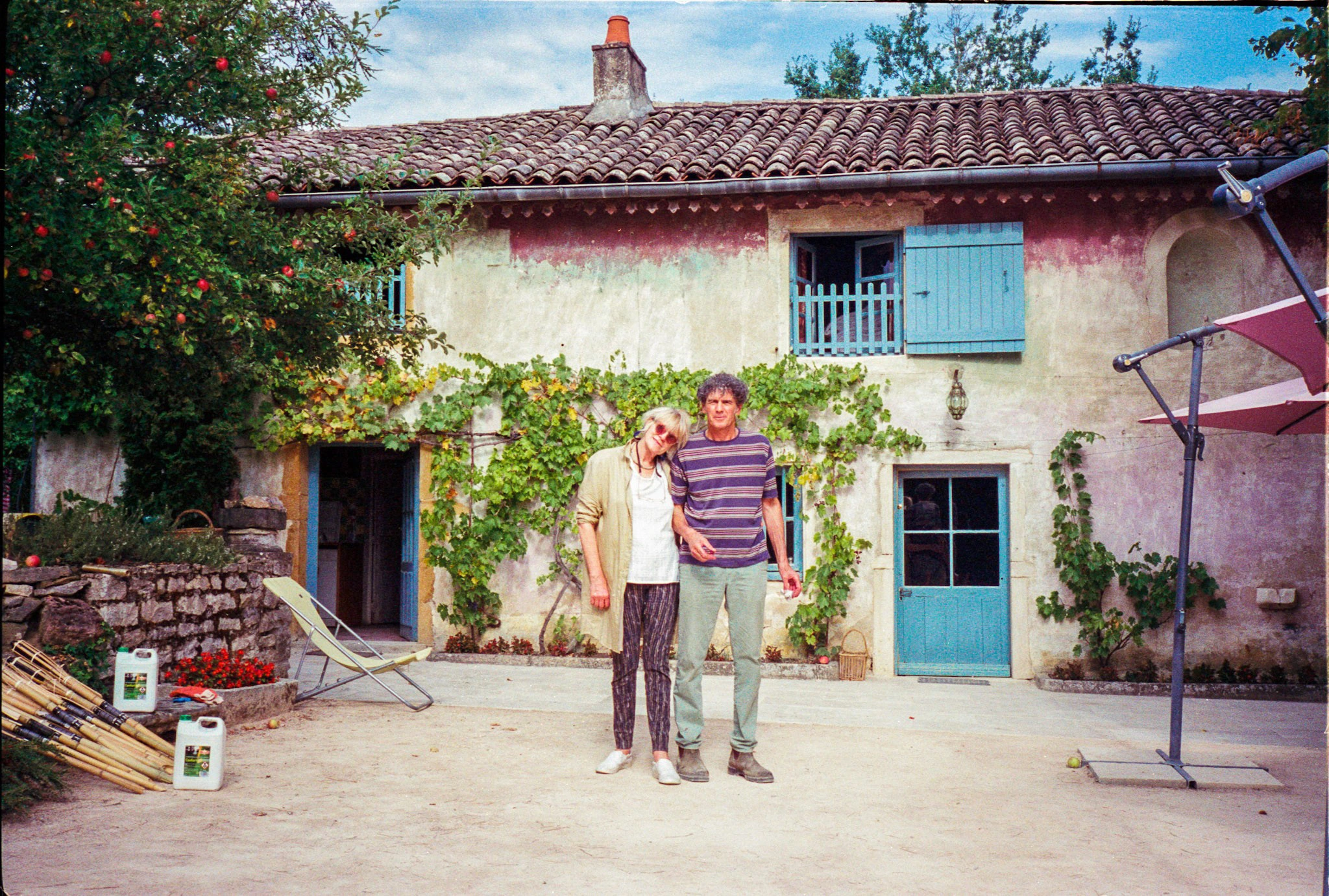 Couple outside blue-shuttered house.