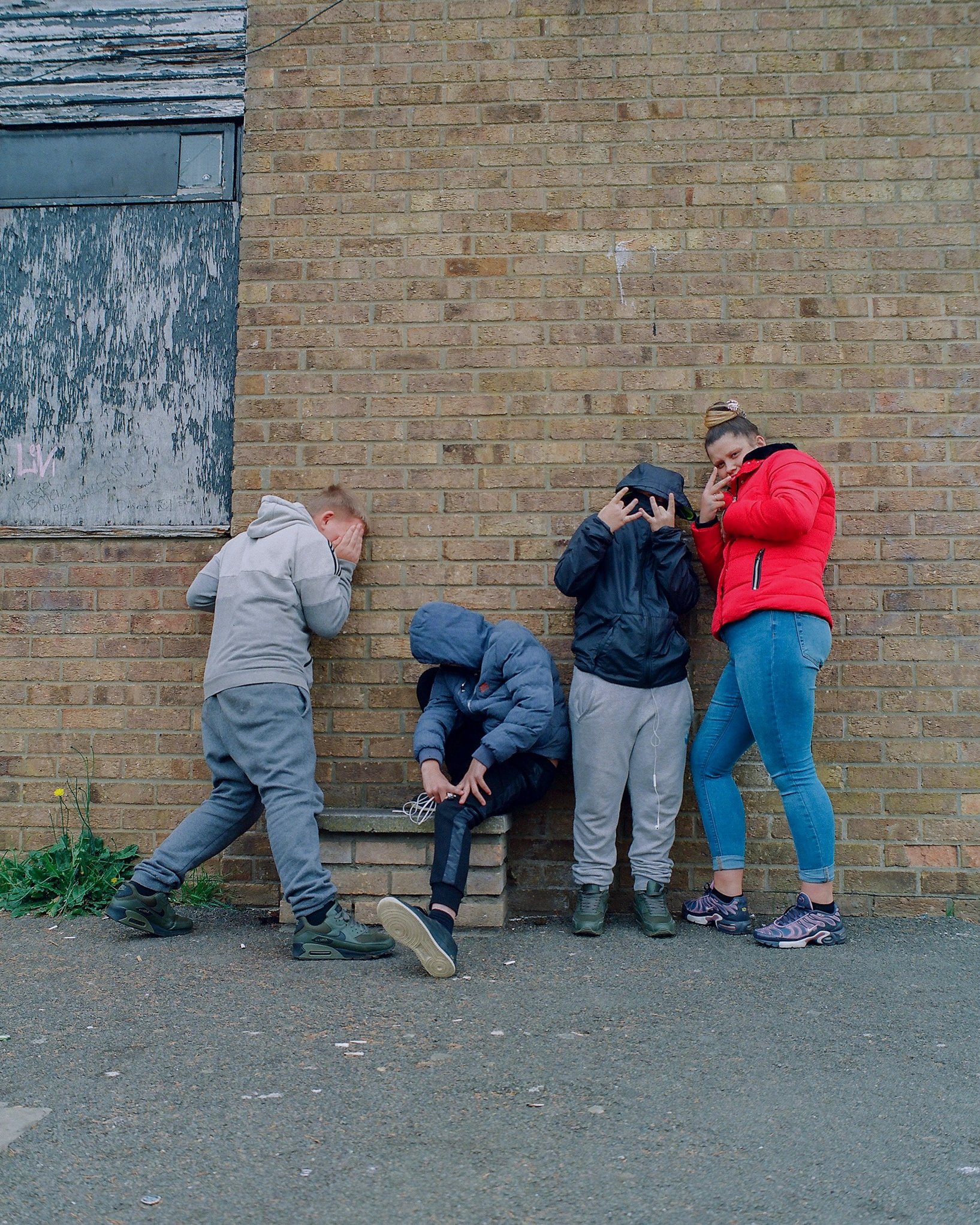 Group leaning against brick wall.