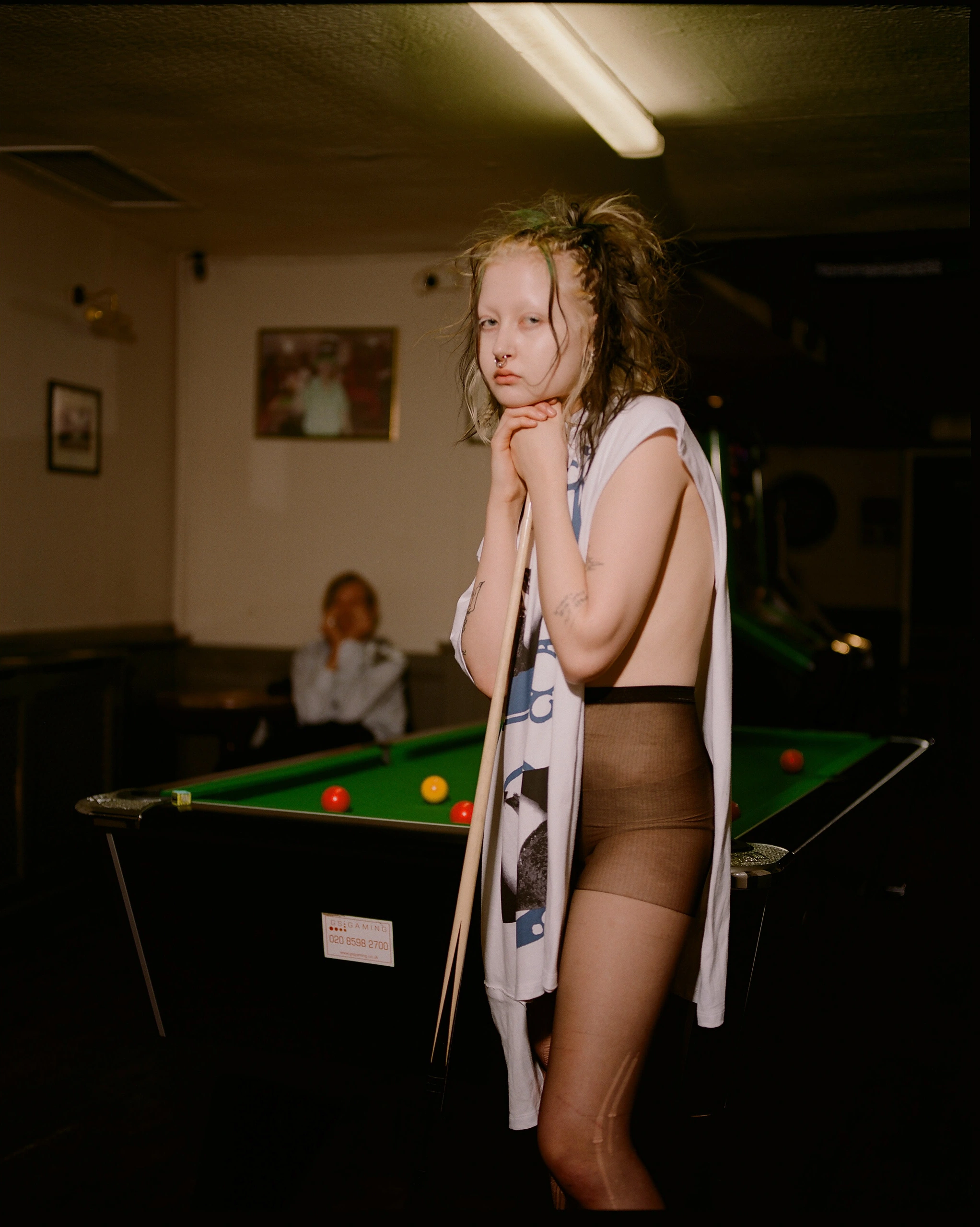 Woman beside pool table.