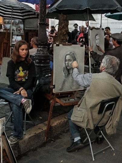 Street artist painting seated sitter.