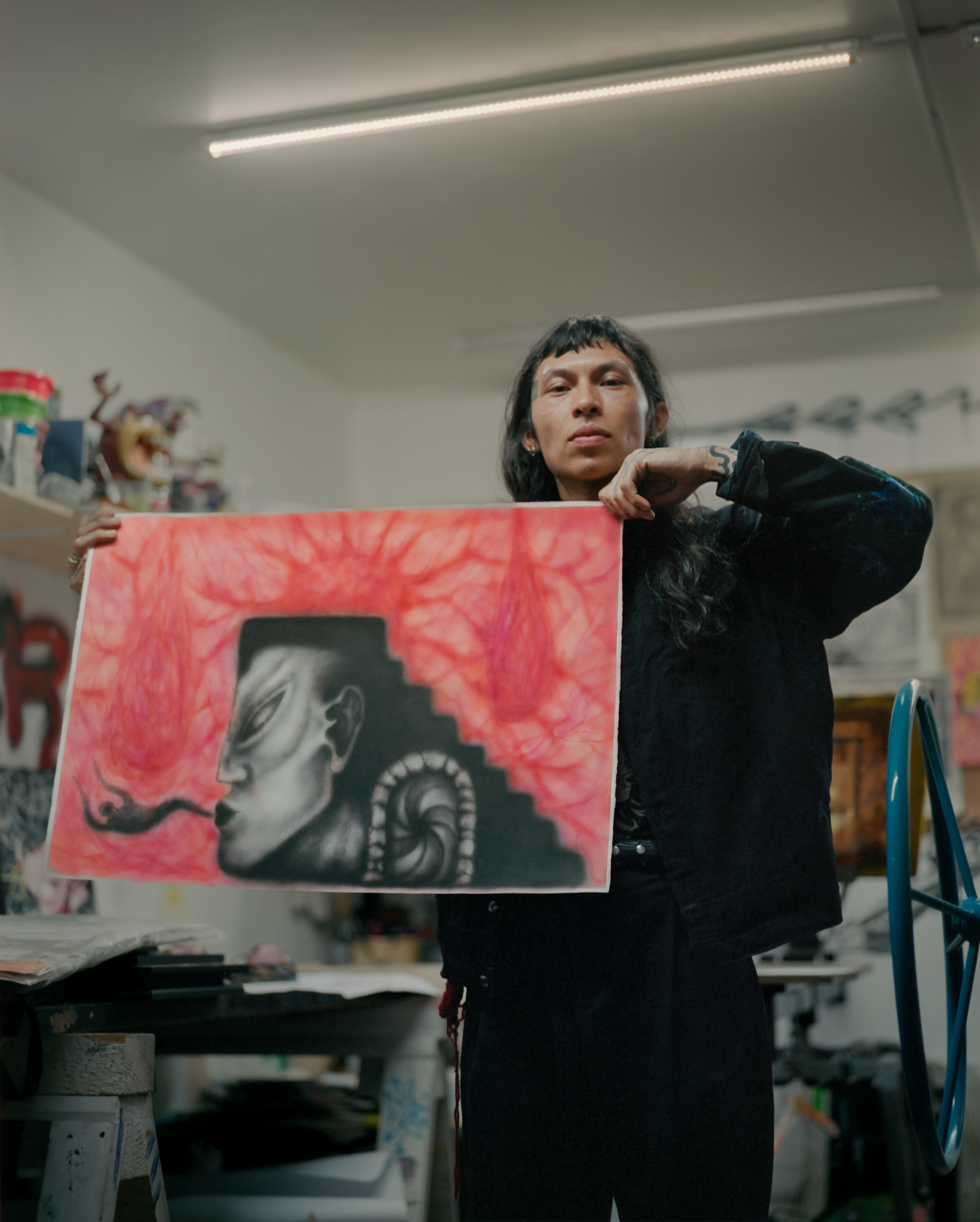 A person holding a painting in a studio.