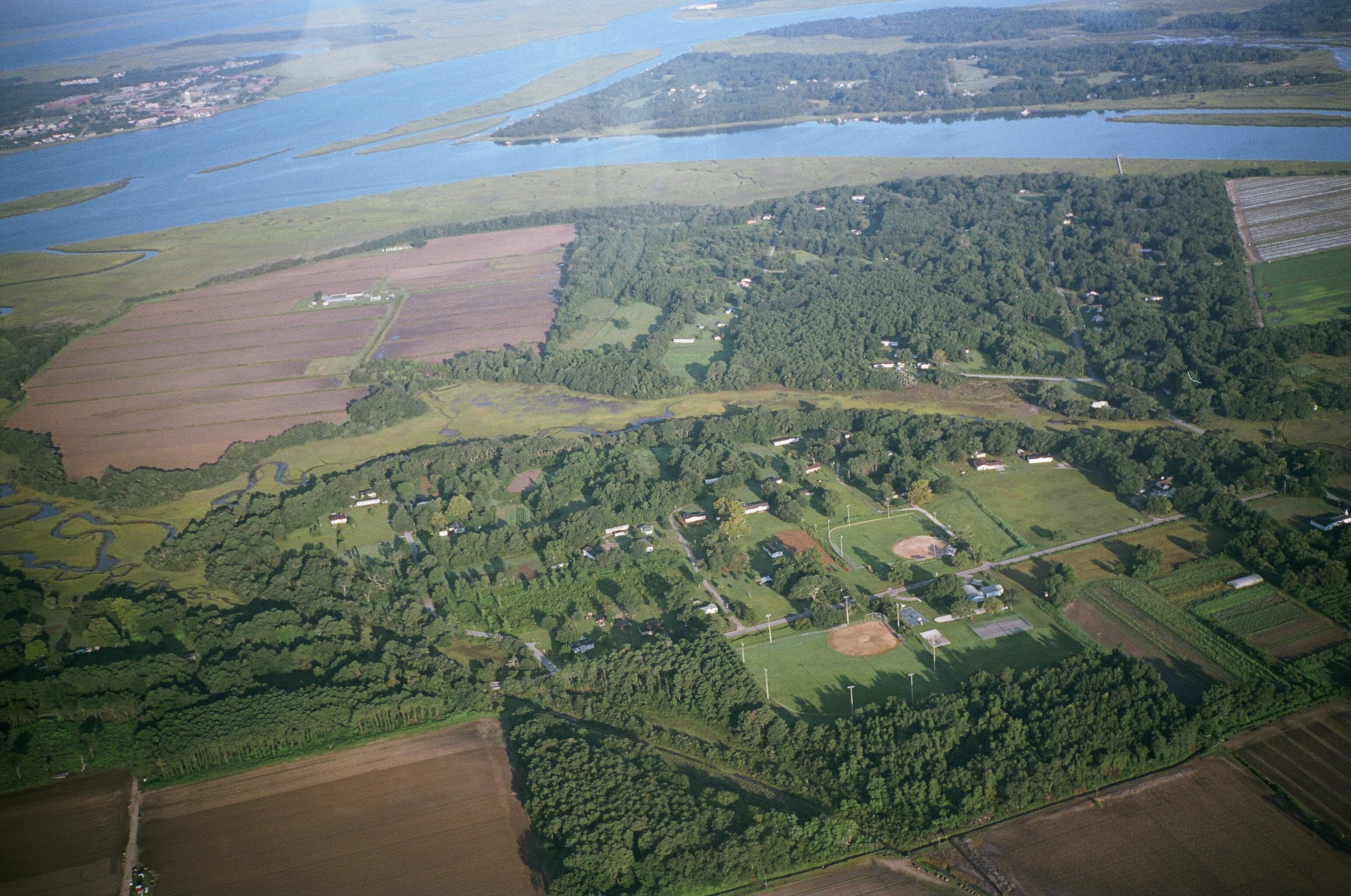 An aerial view of fields, homes and tidal waterways.