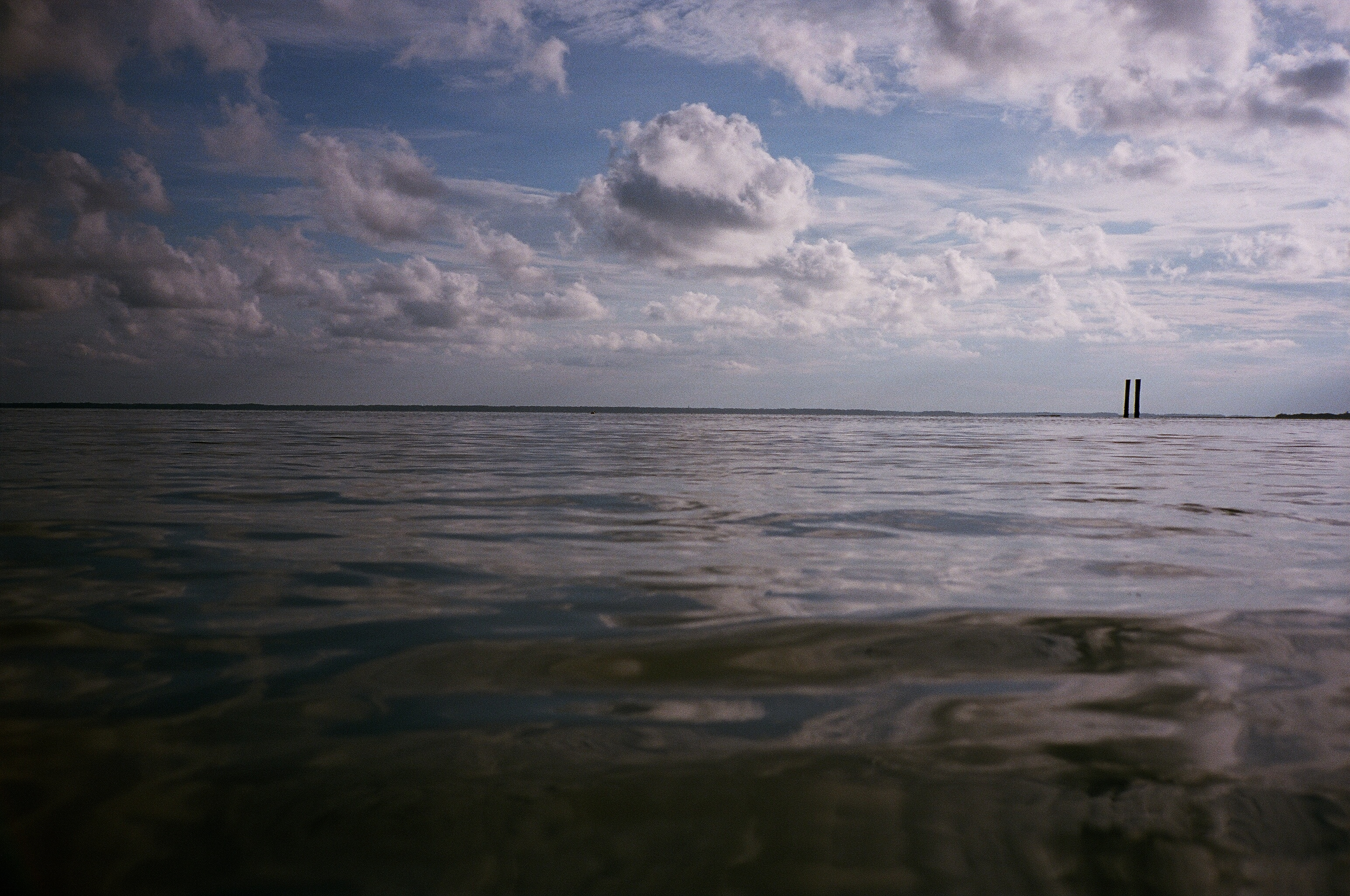 A low view across rippling water beneath a cloudy sky.