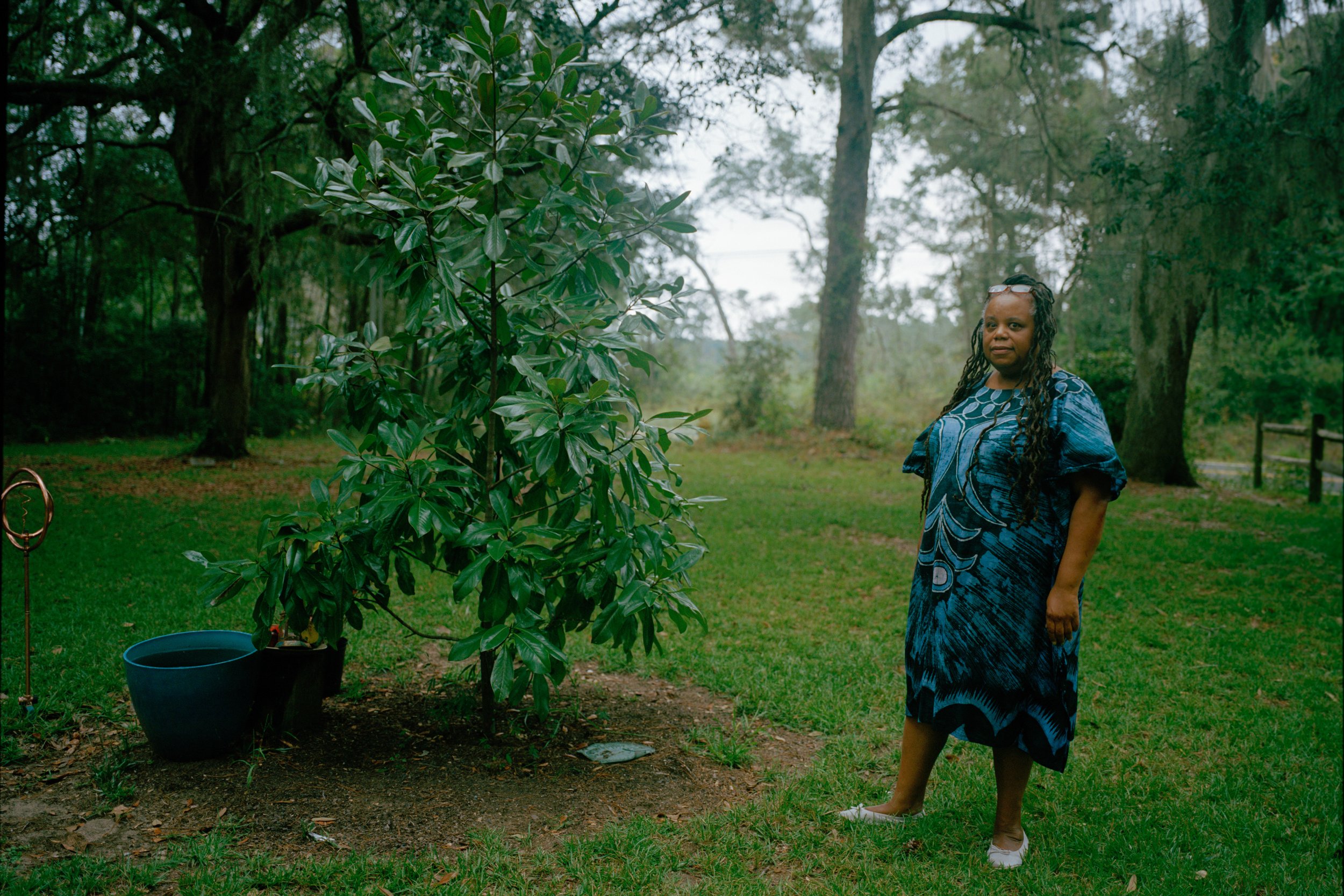 Sandra Boyd standing in her garden among plants and trees.