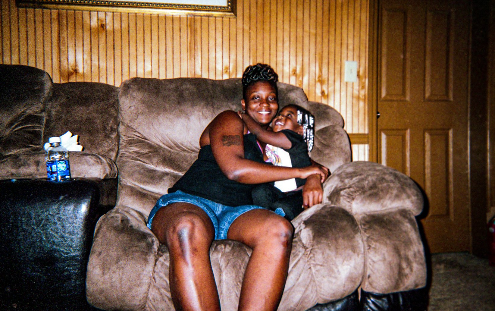 Two people holding one another on a sofa.