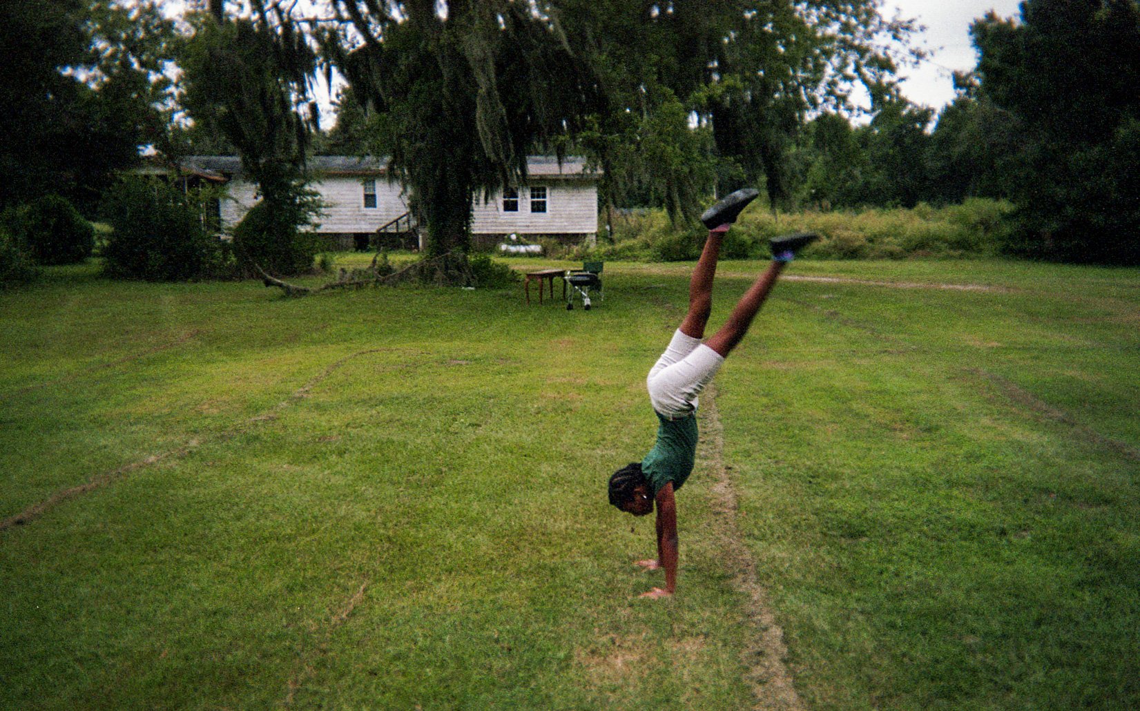 A child doing a handstand on a lawn.
