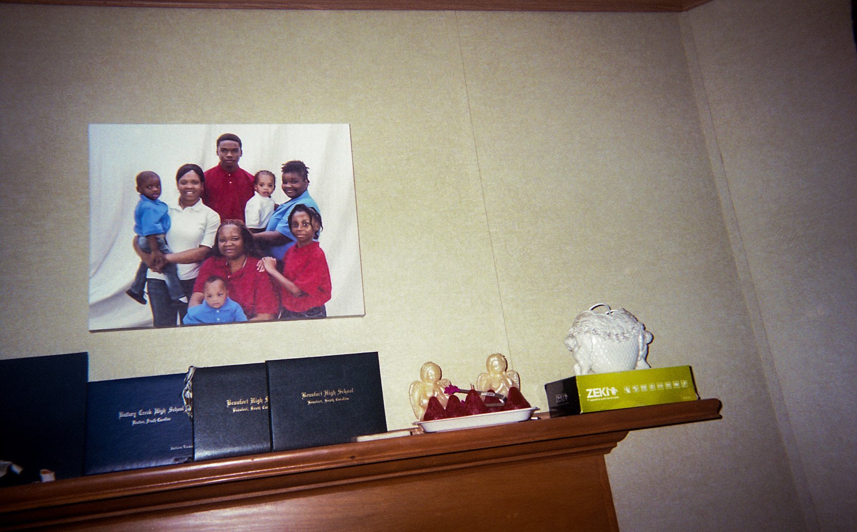 A family portrait on a wall above framed certificates and small objects.