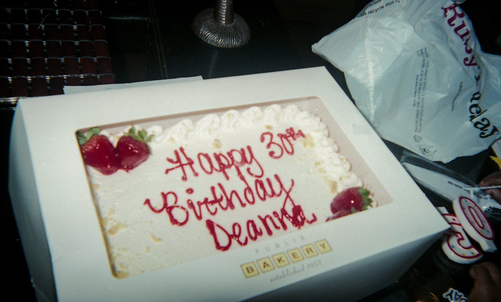 A decorated birthday cake in an open box.
